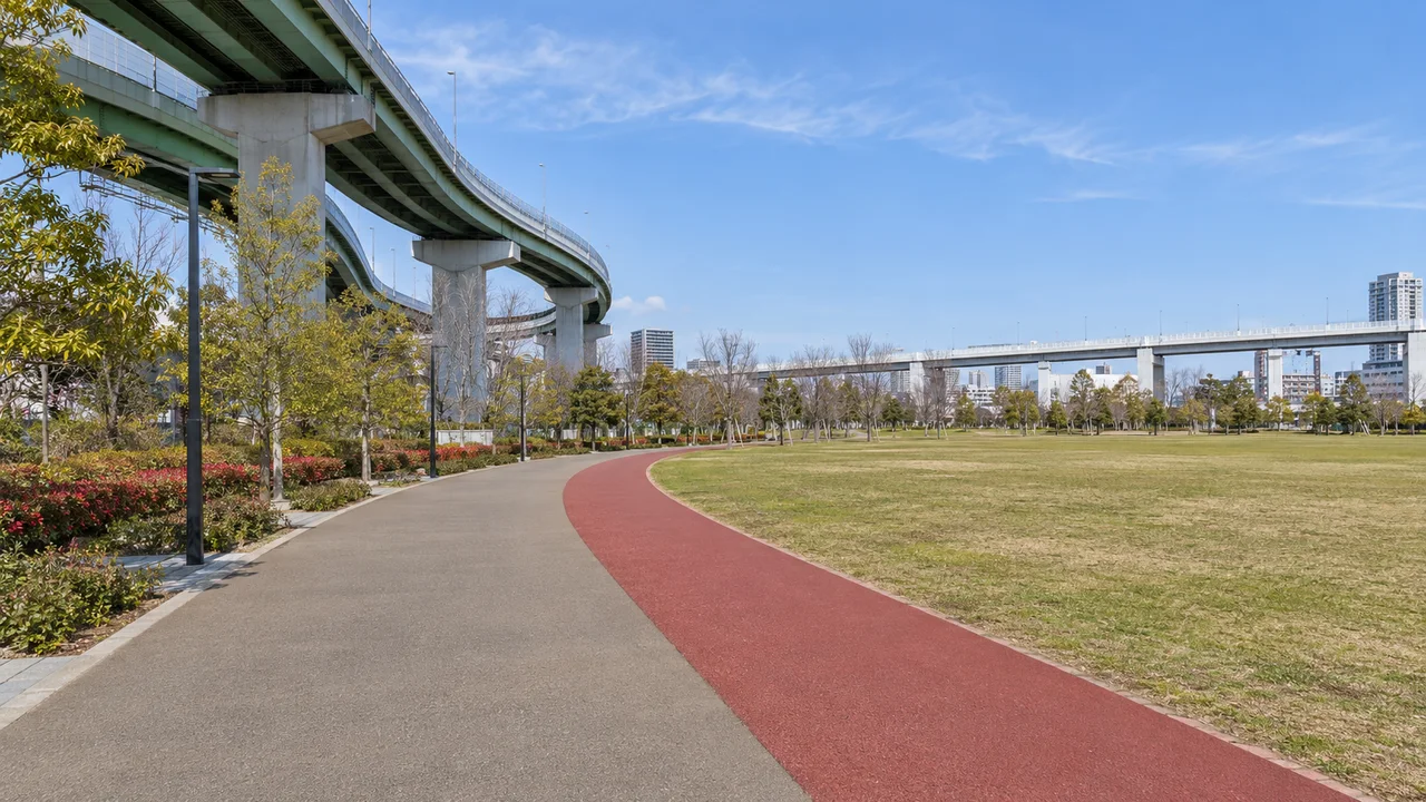 芝生広場沿いの赤い走路（AI生成の参考イメージ）