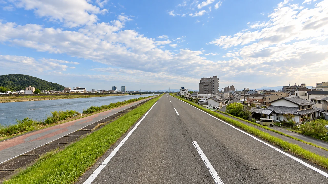 金華橋の手前を曲がり、競技場へ・金華橋へ向かう川沿いの道(AI生成の参考イメージ)