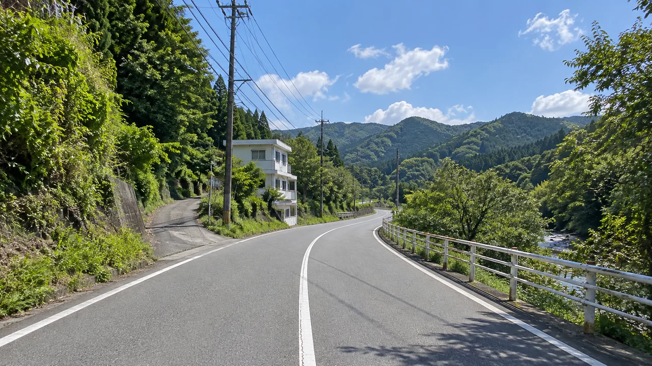揖斐峡大橋の先で、坂の区間へ・揖斐峡沿いの山道・北北西向き(AI生成の参考イメージ)